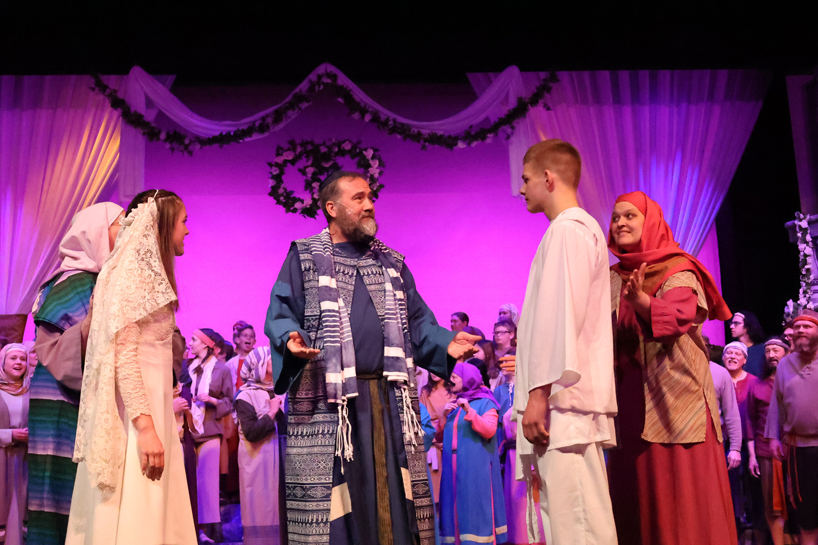 A bride and groom with a rabbi and wedding guests.